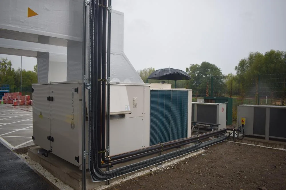 Externally mounted packaged heat pump AHU with its pipework run along the building elevation