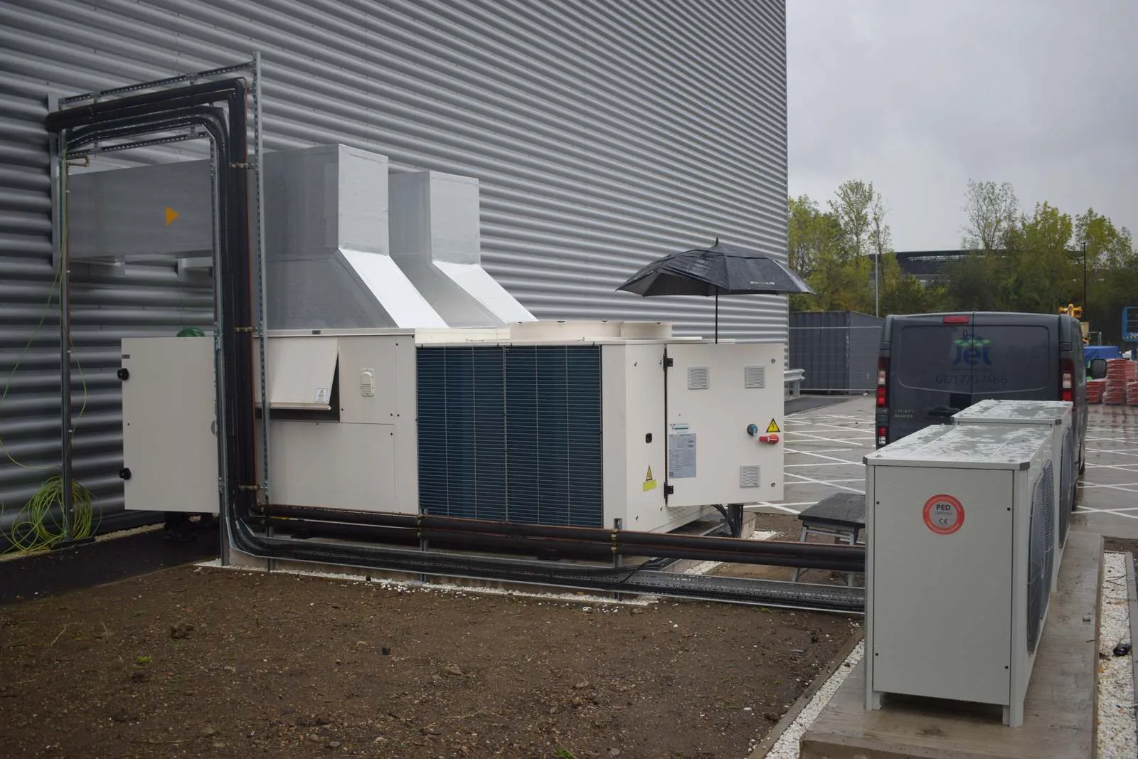 The packaged heat pump air handling unit mounted outside the AIT Worldwide warehouse in Feltham, with a Jet van beside it