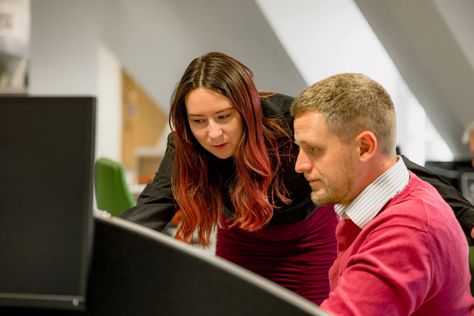 Two colleagues reviewing work together at a computer screen